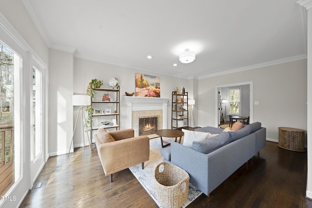 living area with a warm lit fireplace, ornamental molding, wood finished floors, and baseboards