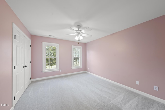 unfurnished room featuring carpet, visible vents, baseboards, and a ceiling fan