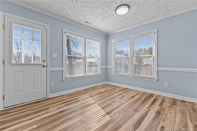 interior space featuring light wood finished floors, baseboards, visible vents, and a textured ceiling