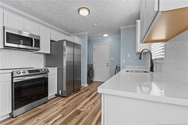 kitchen featuring light countertops, appliances with stainless steel finishes, a sink, and white cabinets