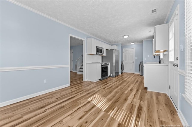 unfurnished living room with ornamental molding, light wood-type flooring, visible vents, and a textured ceiling