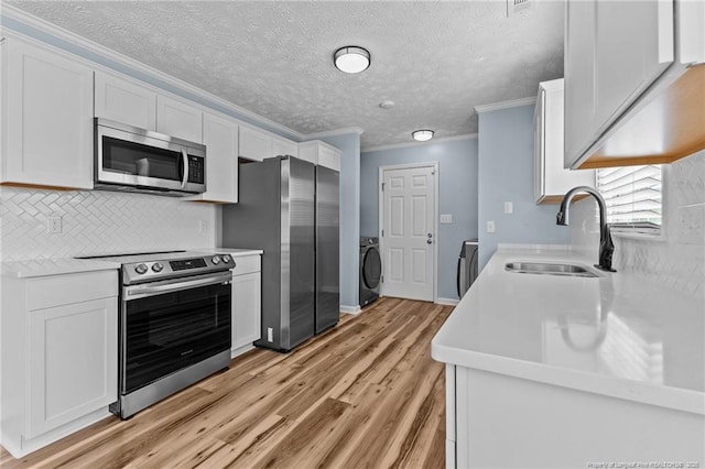 kitchen with a sink, white cabinetry, stainless steel appliances, and light countertops