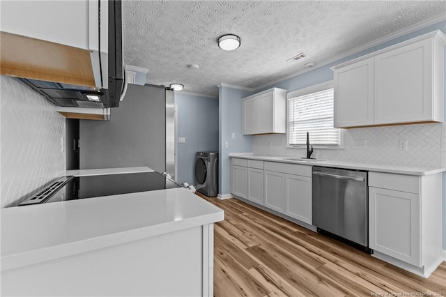 kitchen with light countertops, washing machine and dryer, white cabinetry, and stainless steel dishwasher