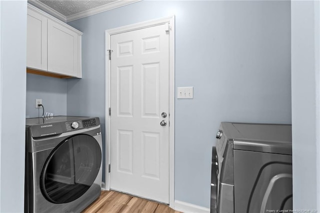 clothes washing area with cabinet space, light wood finished floors, ornamental molding, independent washer and dryer, and a textured ceiling