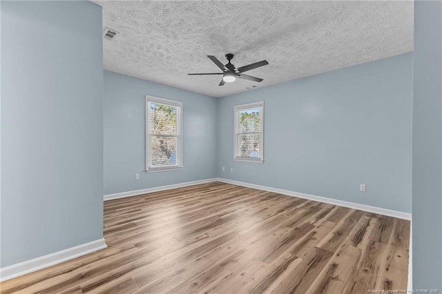 empty room featuring light wood-type flooring, baseboards, visible vents, and a ceiling fan