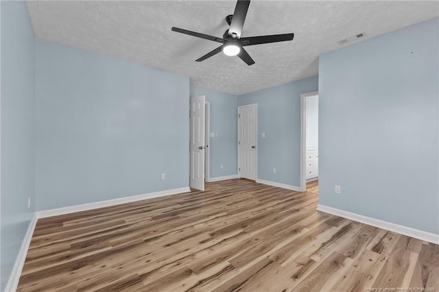 spare room with visible vents, baseboards, light wood-style flooring, ceiling fan, and a textured ceiling