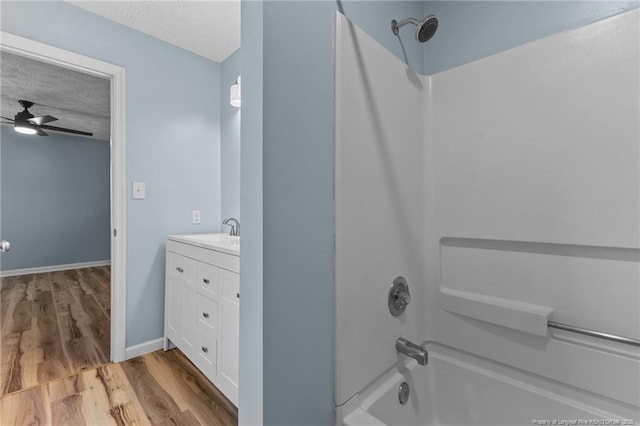 bathroom with a textured ceiling, ceiling fan, shower / bath combination, wood finished floors, and vanity