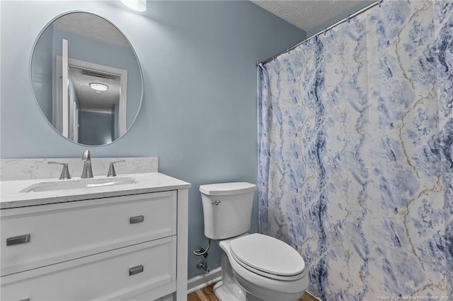 bathroom with a textured ceiling, curtained shower, toilet, vanity, and baseboards