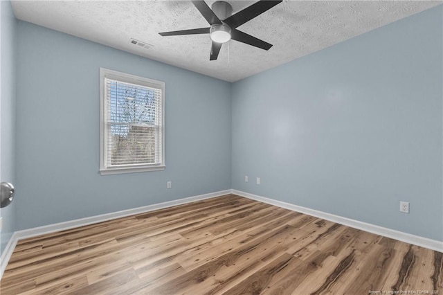 unfurnished room featuring light wood-style floors, visible vents, a textured ceiling, and baseboards