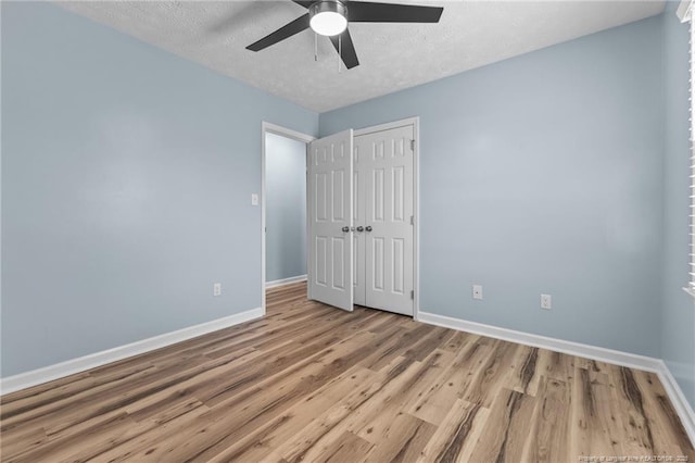 unfurnished bedroom with light wood-style floors, a textured ceiling, and baseboards