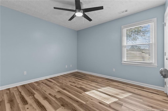 empty room with visible vents, baseboards, a textured ceiling, and light wood finished floors