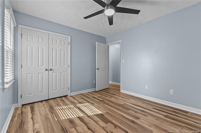 unfurnished bedroom with light wood-type flooring, a closet, and baseboards