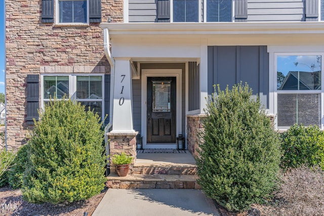 view of exterior entry featuring stone siding and board and batten siding