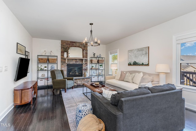 living area featuring dark wood-style floors, a fireplace, baseboards, and an inviting chandelier