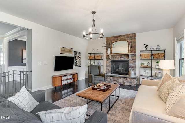 living area with baseboards, a stone fireplace, wood finished floors, and an inviting chandelier