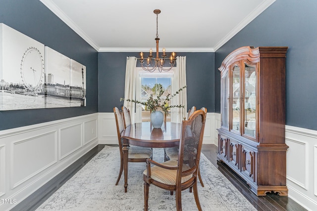 dining area featuring a chandelier, dark wood-style flooring, and wainscoting