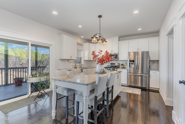 kitchen featuring light stone counters, decorative backsplash, appliances with stainless steel finishes, dark wood-type flooring, and white cabinets