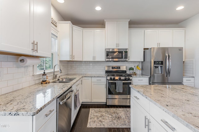 kitchen featuring light stone counters, a sink, white cabinets, appliances with stainless steel finishes, and dark wood-style floors