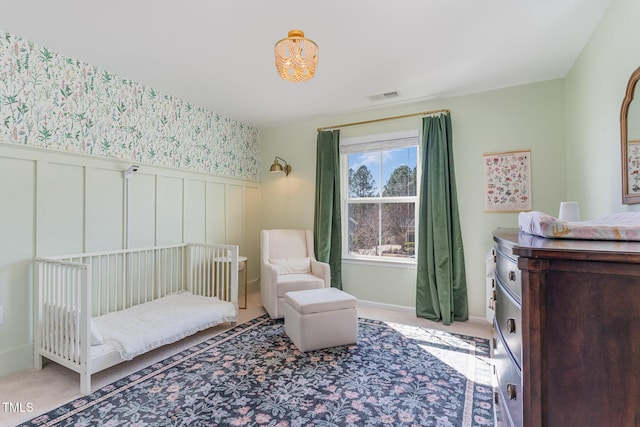 bedroom featuring a wainscoted wall, visible vents, wallpapered walls, and light colored carpet