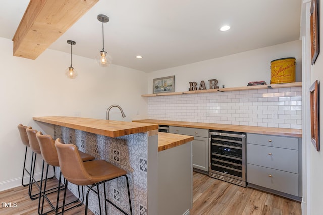 bar with light wood finished floors, beverage cooler, tasteful backsplash, pendant lighting, and recessed lighting