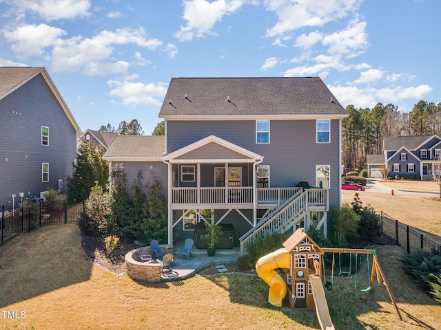 back of house featuring an outdoor fire pit, a fenced backyard, a yard, a patio area, and a playground