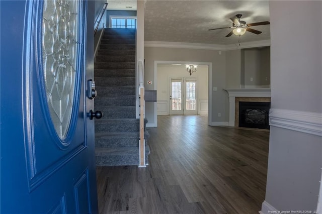 entrance foyer with dark wood-style flooring, a fireplace, ornamental molding, a textured ceiling, and stairs