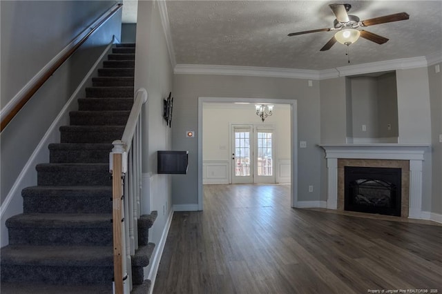 interior space with ornamental molding, a tile fireplace, a textured ceiling, and wood finished floors