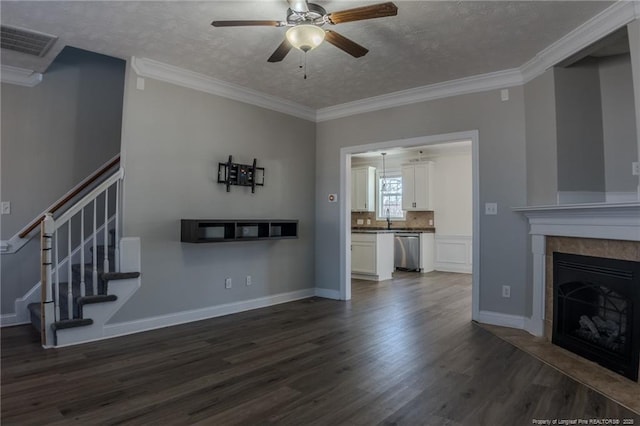 unfurnished living room with dark wood-type flooring, a tile fireplace, visible vents, and crown molding