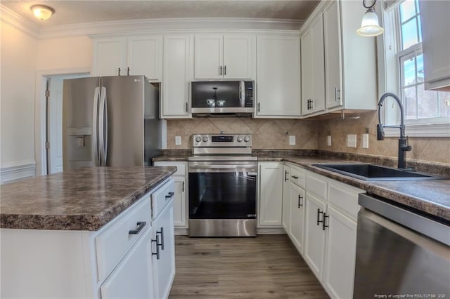 kitchen featuring appliances with stainless steel finishes, dark countertops, white cabinetry, and a sink