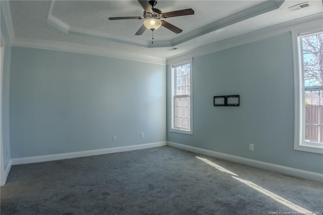 carpeted spare room featuring ornamental molding, a tray ceiling, visible vents, and baseboards