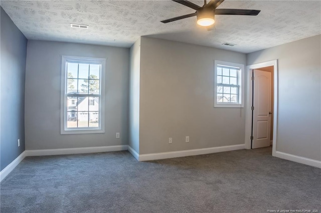 carpeted spare room with a textured ceiling, baseboards, visible vents, and a ceiling fan