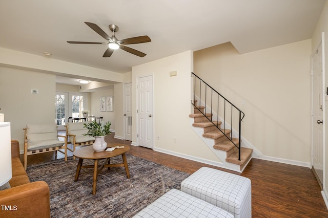 living area with a ceiling fan, stairway, baseboards, and wood finished floors