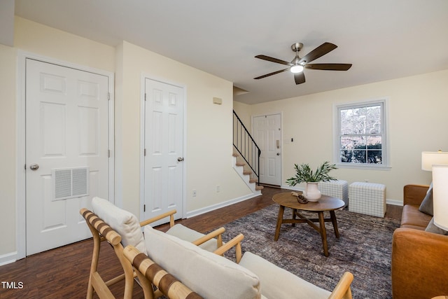 living room with dark wood-style flooring, visible vents, ceiling fan, baseboards, and stairs