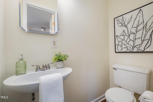 bathroom with toilet, baseboards, and a sink