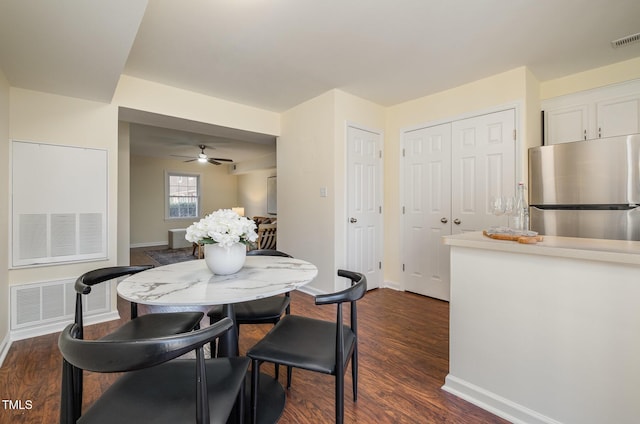 dining room with dark wood-style floors, visible vents, and baseboards