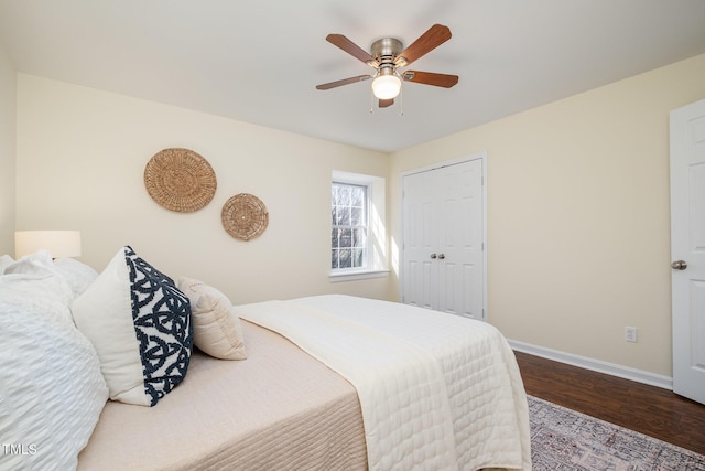 bedroom with a closet, wood finished floors, a ceiling fan, and baseboards