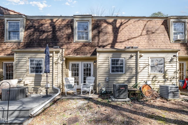 rear view of house featuring a shingled roof, cooling unit, and mansard roof