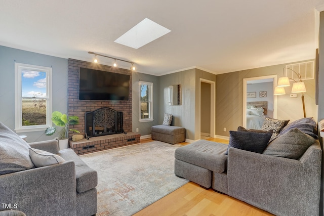 living area with a skylight, visible vents, ornamental molding, wood finished floors, and a brick fireplace