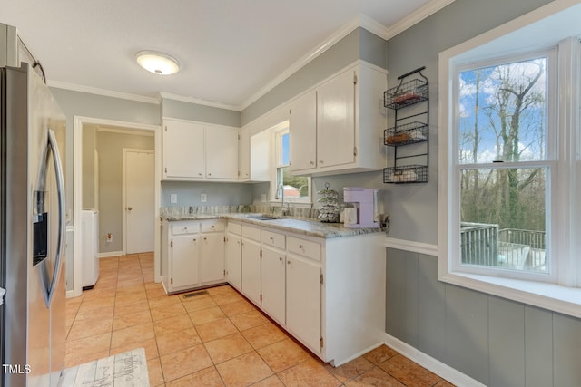 kitchen with a sink, light countertops, stainless steel fridge, and white cabinets