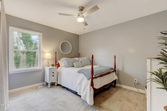 bedroom with visible vents, baseboards, a ceiling fan, and light colored carpet