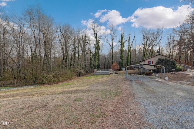 view of street with driveway, a gated entry, and a forest view