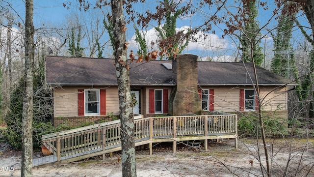 view of front of property with roof with shingles, a chimney, a deck, and brick siding