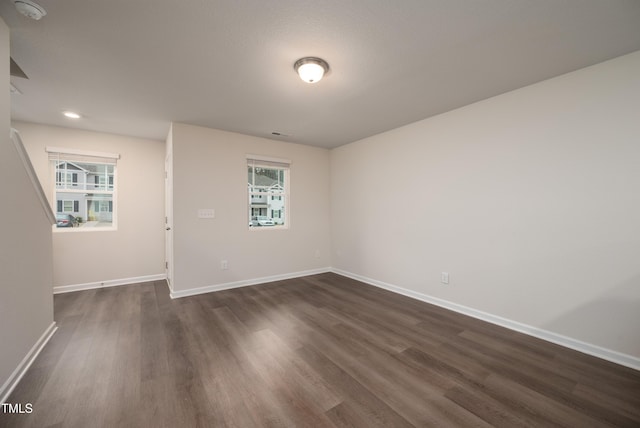 unfurnished room with a healthy amount of sunlight, dark wood finished floors, and baseboards