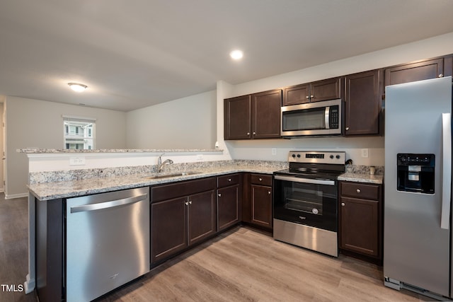 kitchen featuring dark brown cabinetry, appliances with stainless steel finishes, a peninsula, light wood-type flooring, and a sink