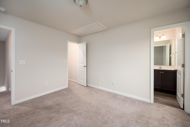 unfurnished bedroom with light carpet, a sink, baseboards, ensuite bath, and attic access