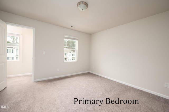 empty room with plenty of natural light, visible vents, baseboards, and carpet flooring