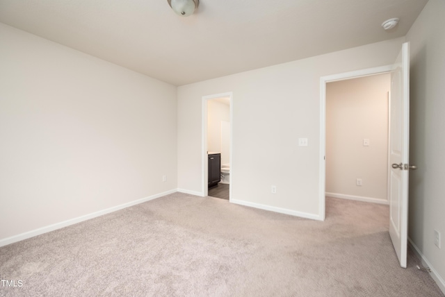 unfurnished bedroom with ensuite bathroom, carpet flooring, and baseboards