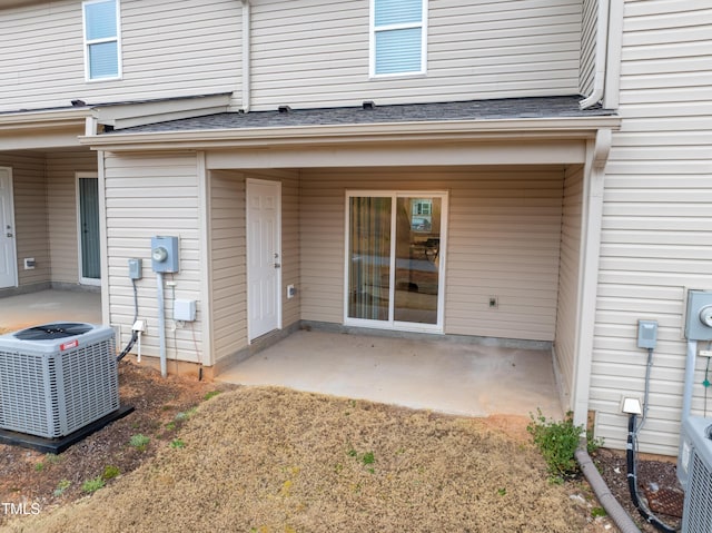 rear view of property featuring a patio area, central AC unit, and roof with shingles