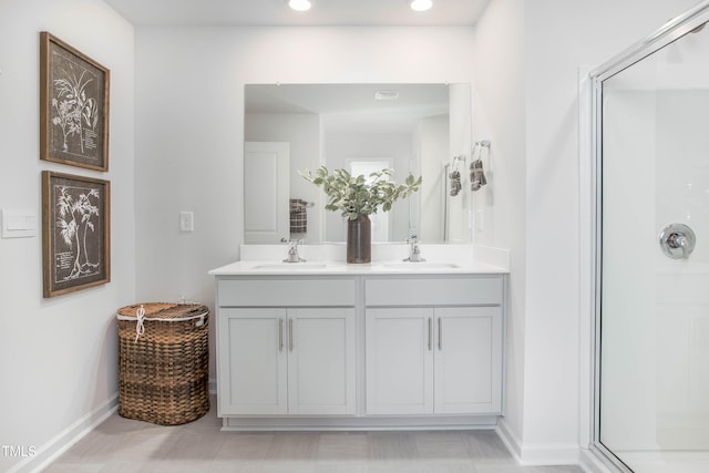 bathroom featuring baseboards, double vanity, a sink, and a shower stall