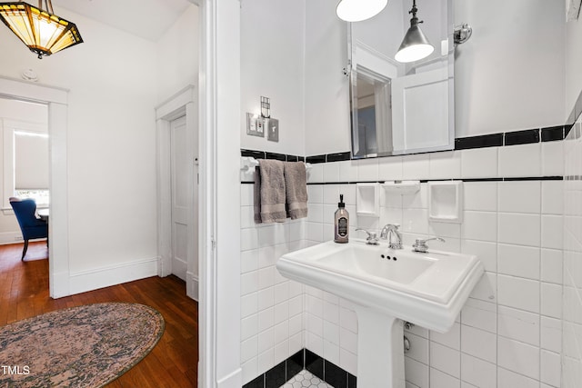 bathroom featuring a sink, baseboards, tile walls, and wood finished floors